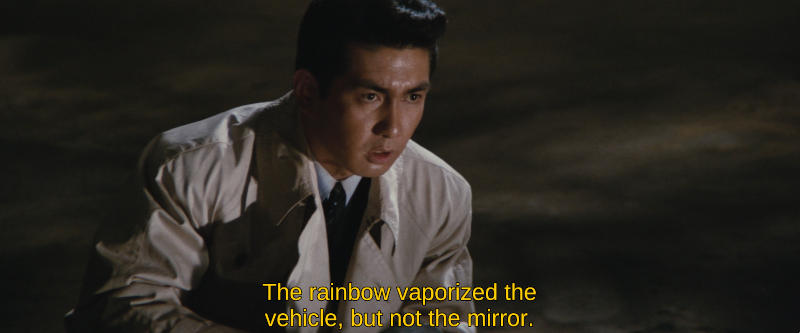 Color image. A man kneels on a bit of blasted earth and looks offscreen pensively. The subtitle reads, The rainbow vaporized the vehicle, but not the mirror.