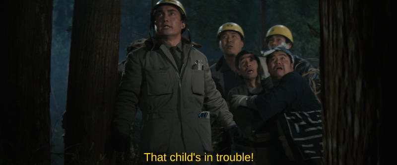 Several workmen stand in the woods, appearing frightened and looking offscreen. The subtitle reads, That child's in trouble!